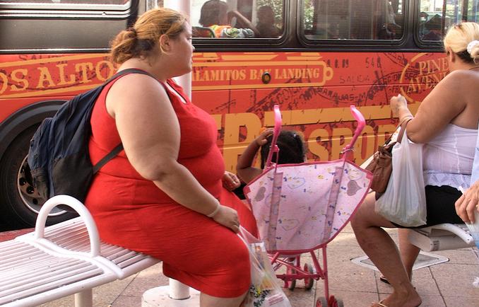 Une femme obèse assise sur un banc