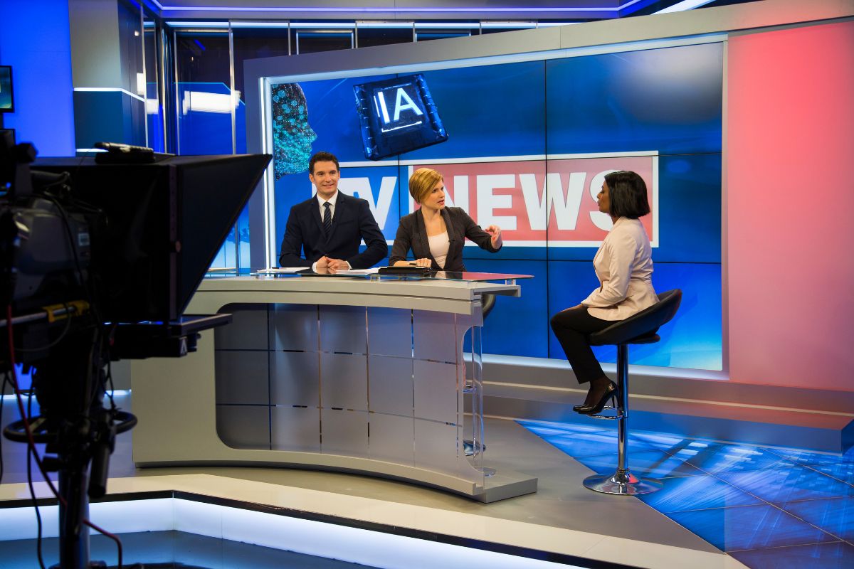 Échanges sur un plateau de télévision au sujet des faux reportages télé créés par l'IA pour promouvoir des applications crapuleuses.