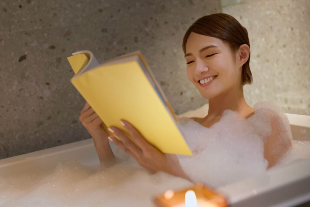 Une femme profite à la fois d'un bain chaud et de la lecture pour se détendre avant de se coucher et améliorer son sommeil naturellement. 