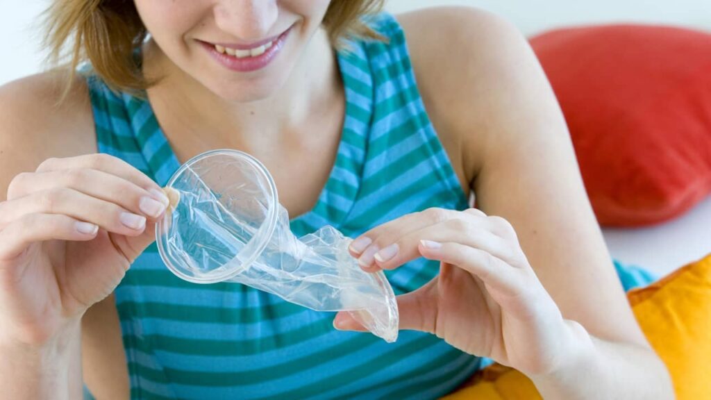 femme qui ouvre un preservatif feminin