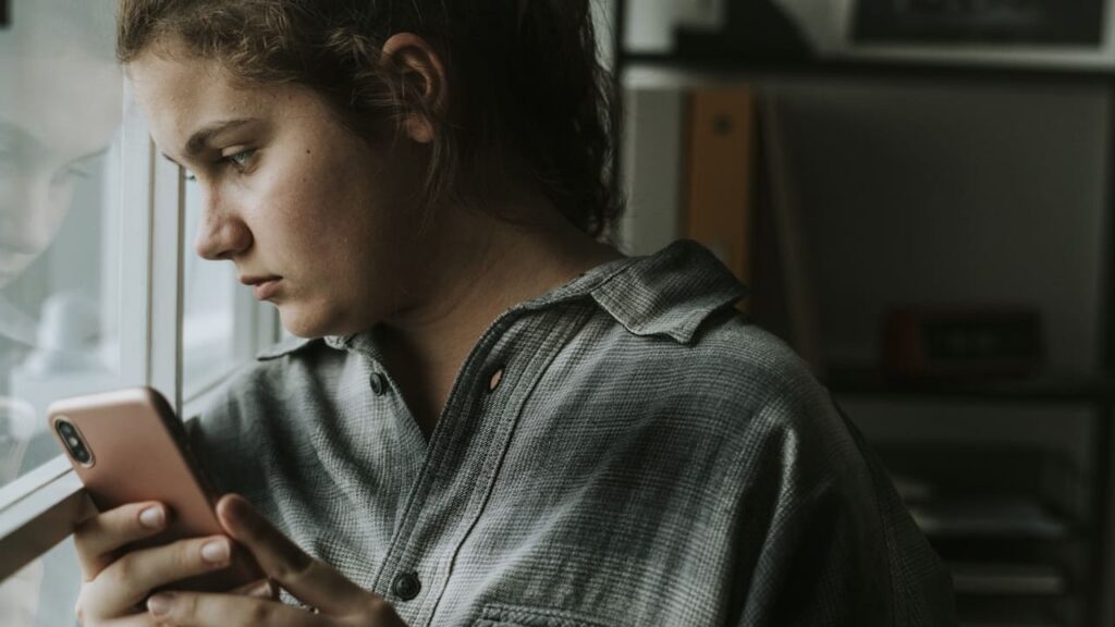 femme triste regarde fenetre telephone