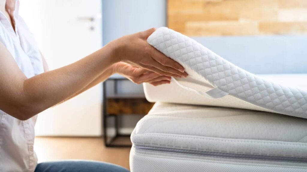 Surmatelas : avantages et inconvénients, faut-il vraiment en acheter un ? femme met surmatelas